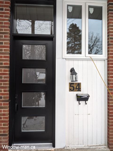 Single black front door installation. Contemporary trendy shaker style. 4 lite Acid etched glass. 8 foot door 96 inch transom 130 inches. Lorraine retro collection